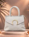 White textured handbag with top handles and gold circular hardware.
