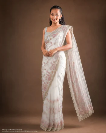 Elegant woman wearing a white saree with delicate pink floral embroidery and a scalloped embellished border