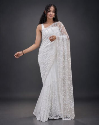 A beautiful Sri Lankan bride wearing an elegant white bridal saree with intricate floral embroidery and delicate lace detailing, posing in a studio