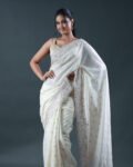 Off-white soft brocade saree with subtle gold booti weave and pastel multicolor floral embroidered borders