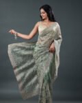 Sage green organza saree featuring delicate silver thread floral embroidery throughout with an embellished border