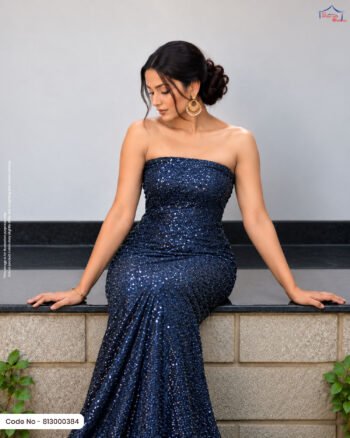 A woman sitting on a ledge wearing a strapless evening gown made of royal navy blue sequined fabric